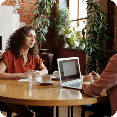 Tucows logo over an image of two people talking while working on laptops
